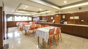 Un hall d’accueil d’hôtel avec plusieurs tables et chaises, un comptoir de réception et une vue sur l’extérieur grâce à de grandes fenêtres.