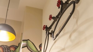 Un vélo fixé au mur, avec des pédales rouges et une chaîne, une lampe suspendue et une vue partielle d’une sculpture verte.