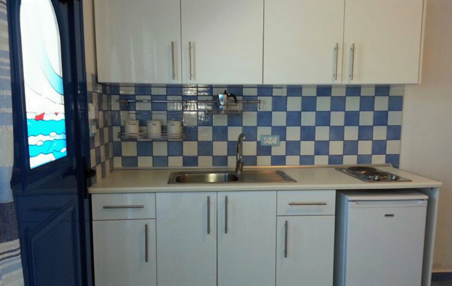 A compact kitchen with a checkered backsplash, a sink, and cabinets.