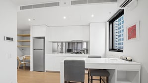 Une cuisine moderne avec des meubles blancs, une cuisinière encastrée et une fenêtre donnant sur le paysage urbain.