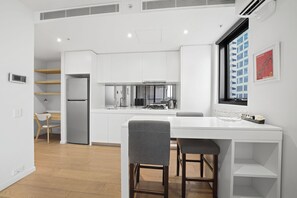 Una cocina moderna con armarios blancos, estufa empotrada y ventana con vista a la ciudad.