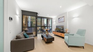 Un salon moderne avec un canapé, une table basse, un meuble pour la télévision et un fauteuil bleu clair.