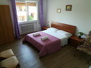 A neatly arranged bedroom with a bed, a bedside table with a plant, a chair, and a wardrobe. - Venice Primavera Guesthouse  (Mestre)