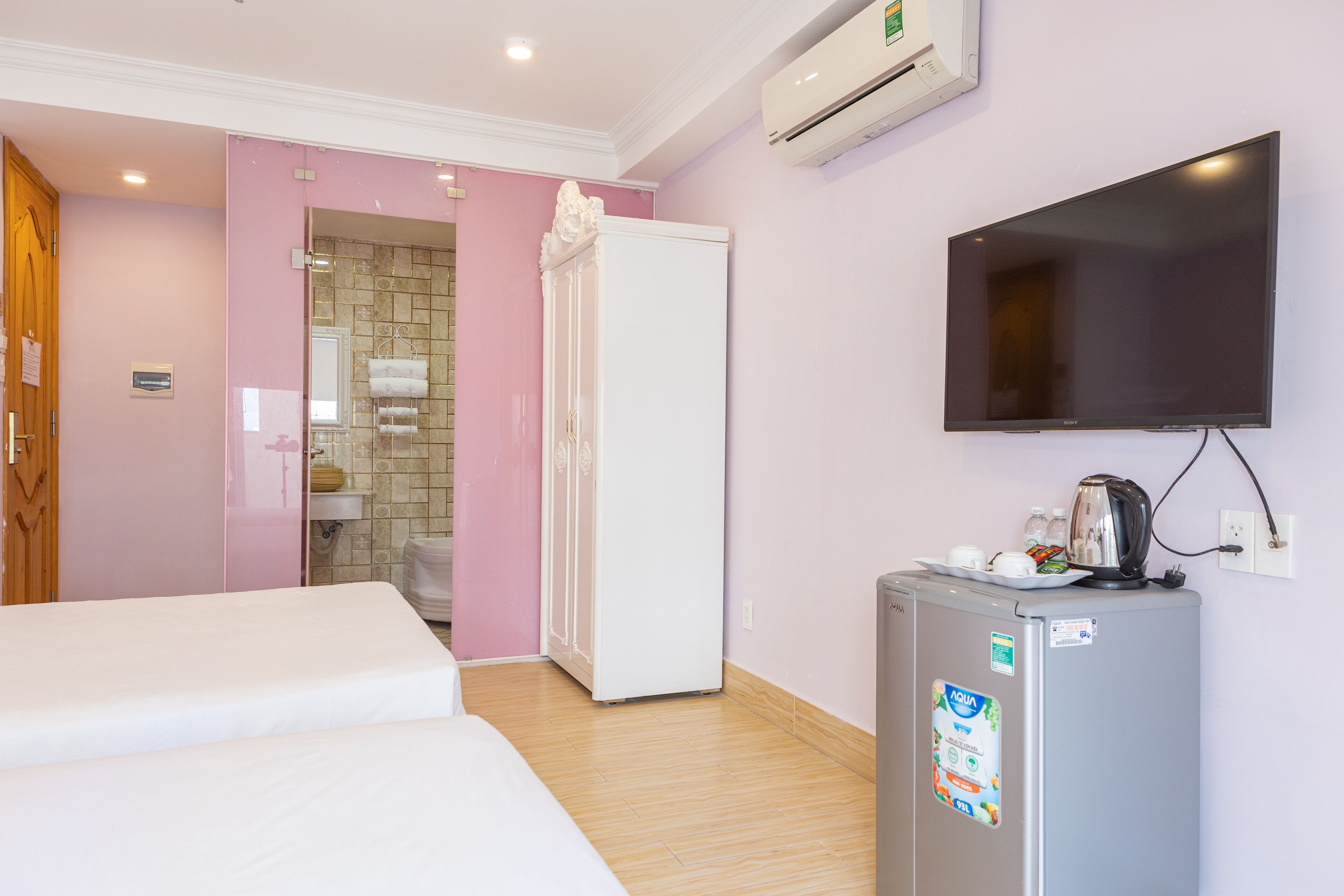 A hotel room with a bed, a refrigerator, a television, and a bathroom with a shower and toilet.