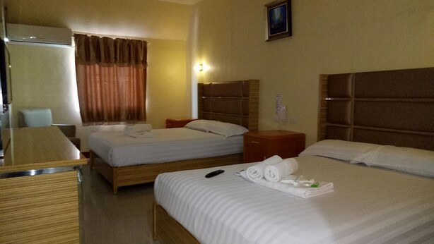 A hotel room with two beds, a desk, a chair, and a window with curtains.