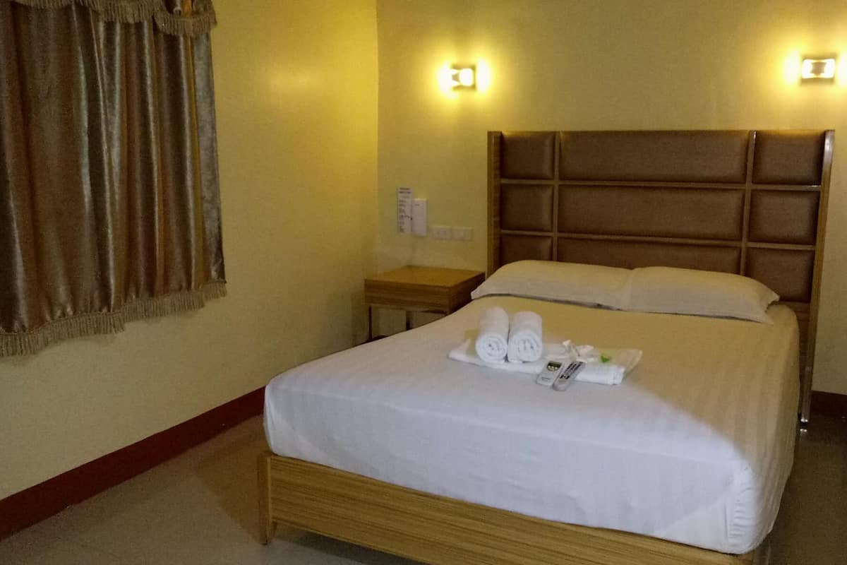 A hotel room with a large bed, a nightstand, and two wall-mounted lights.