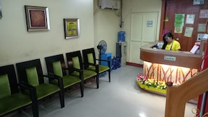 A reception area with a cashier counter, several chairs, and a wall-mounted fan.