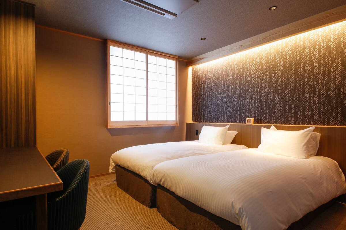 A hotel room with a large bed, a desk, and a window.