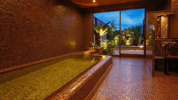 Un área de spa con suelo de baldosas, pared de ladrillo y puerta de cristal que da al exterior.