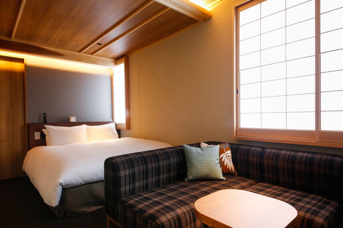 A hotel room with a bed, a sofa, and a window.