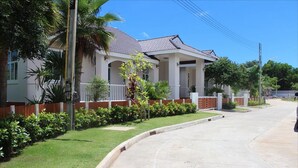 A two-story house with a tiled roof, a front porch, and a well-maintained lawn. - Suanson Paragon Green Villas (Rayong)