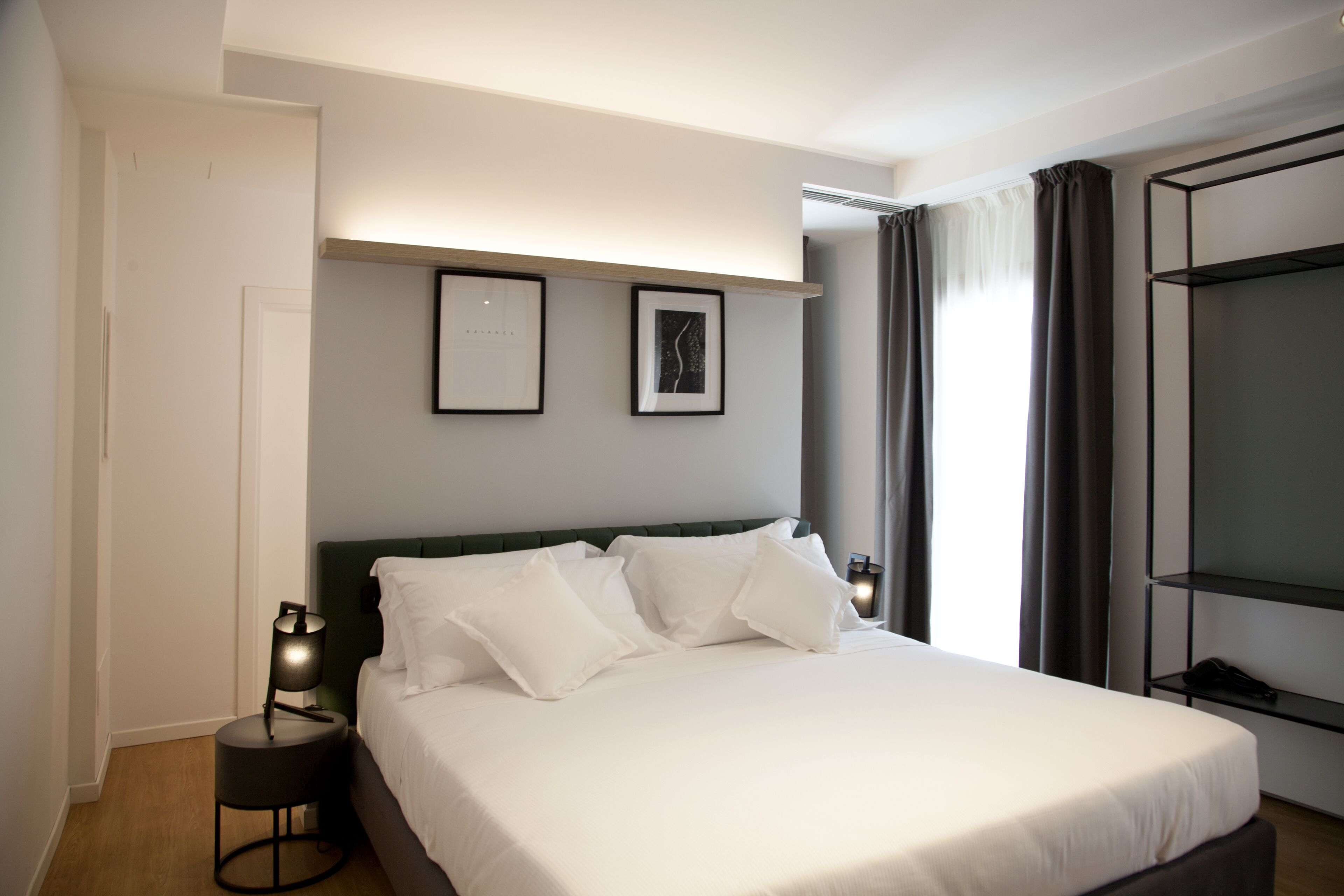 A neatly arranged bedroom with a bed, bedside tables, and a wall-mounted shelf.