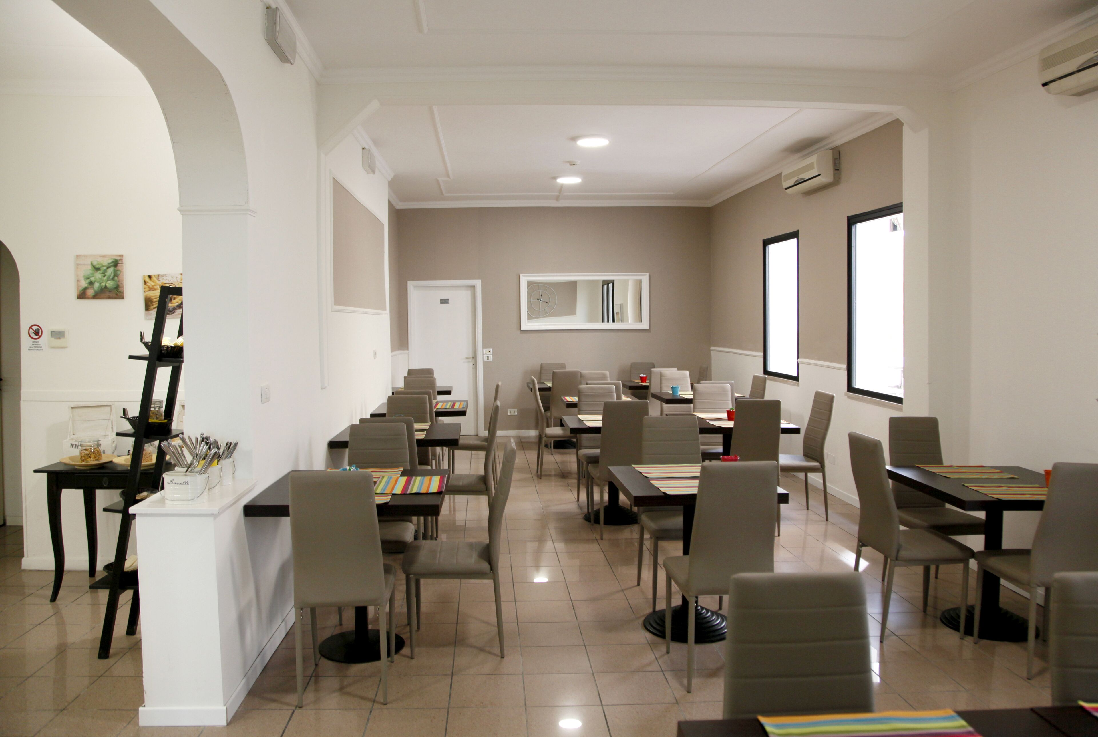 A conference room with multiple tables and chairs, a white reception desk, and a large window providing natural light.