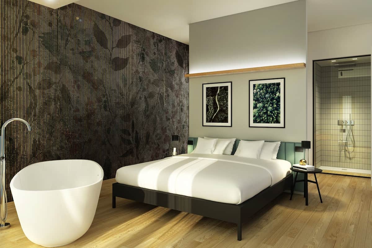Un dormitorio moderno con una cama grande, una bañera blanca y zona de ducha.