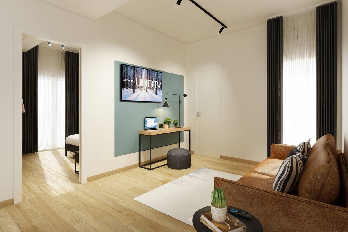 Una sala de estar moderna con un sofá, una mesa de centro, un televisor y un escritorio con una computadora.