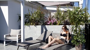 A modern outdoor seating area with lounge chairs and a potted plant. - Meg Lifestyle Hotel (Riccione)