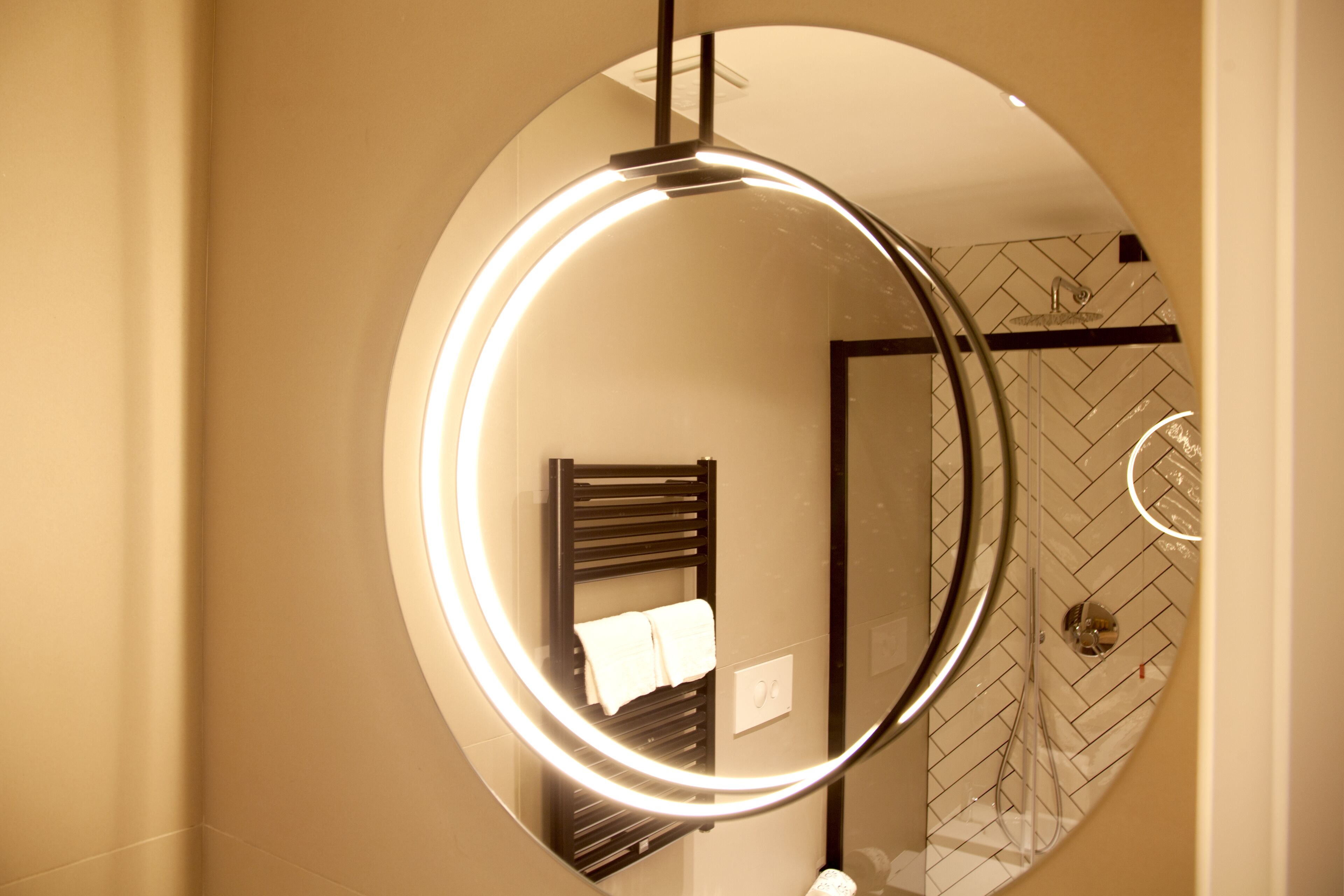 Een badkamer met een ronde spiegel, een handdoekhouder en een douchegedeelte.