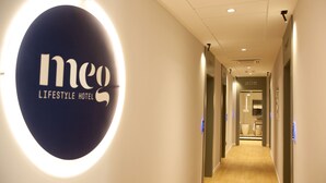 A hallway with a circular sign reading "meo LIFESTYLE HOTEL" and a number "205" on the wall. - Meg Lifestyle Hotel (Riccione)