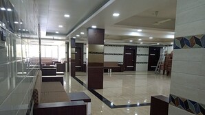 A spacious lobby with a glass wall, seating areas, and a tiled floor. - Sagar Resort (Chhatrapati Sambhajinagar)