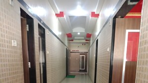 A corridor with tiled walls, green mats on the floor, and doors leading to rooms. - Sagar Resort (Chhatrapati Sambhajinagar)