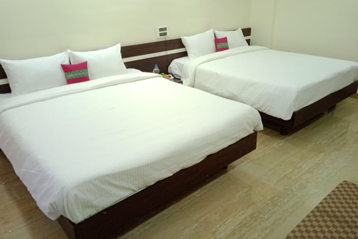 Two single beds with white linens and wooden headboards in a hotel room.