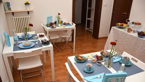 Un coin repas avec deux tables préparées pour le petit-déjeuner, chacune étant mise avec des assiettes, des bols et des tasses.