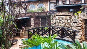 A pool area with a stone wall, potted plants, and a wooden deck. - The Grand Gables (Nairobi)