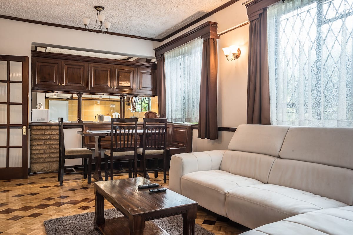 A living room with a sofa, a wooden coffee table, and a dining area with chairs and a table.