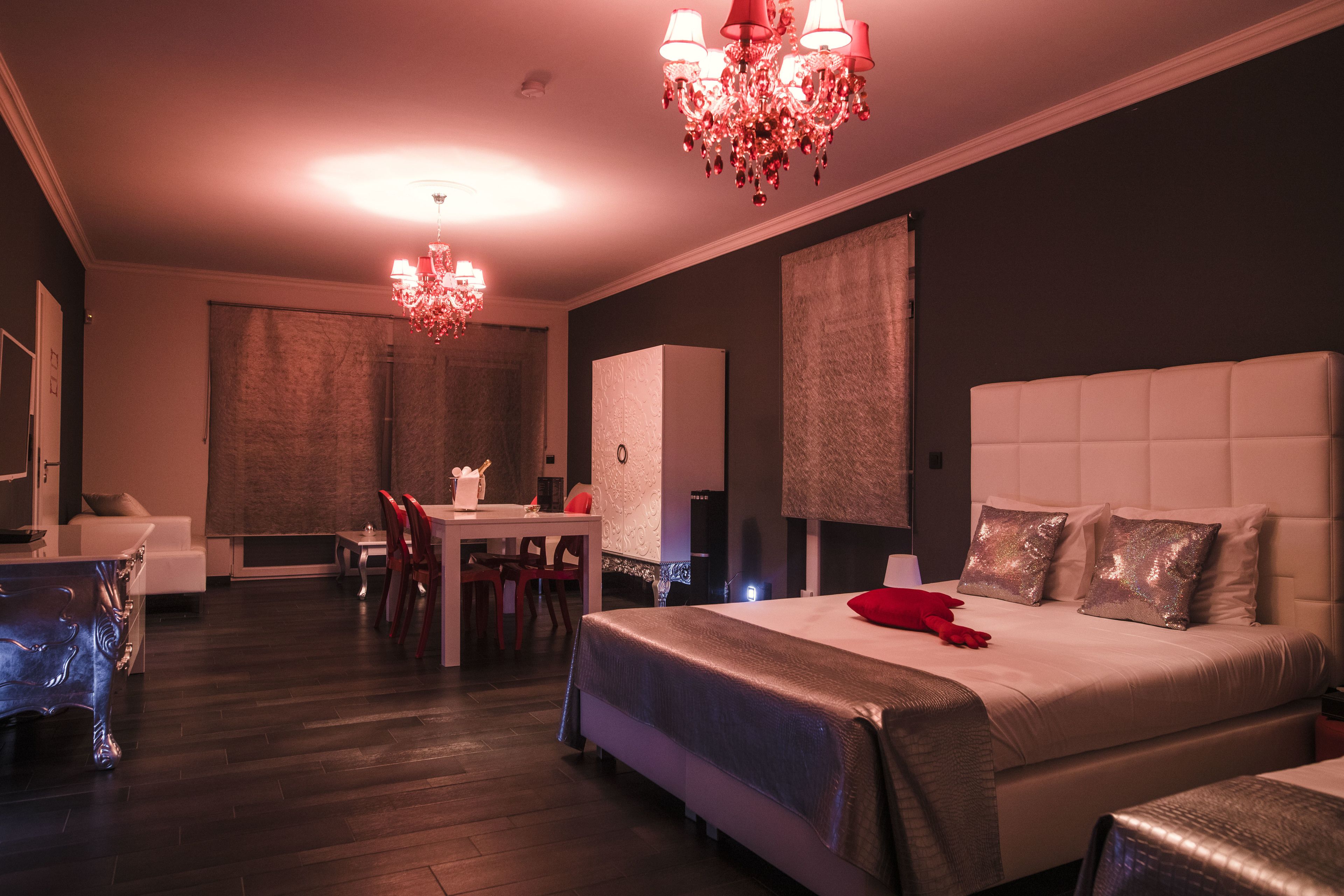 A modern hotel room with a large bed, a desk, and a chandelier.
