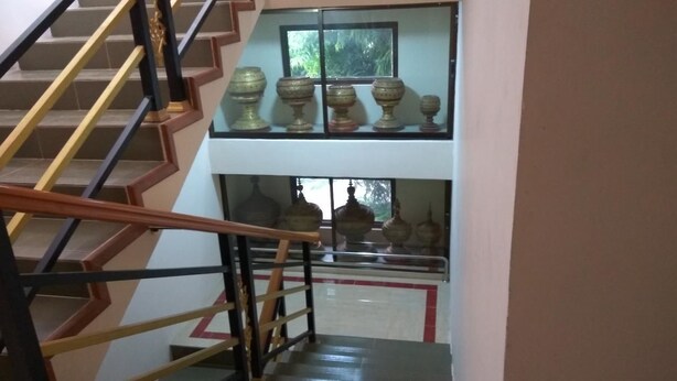 A staircase with a wooden handrail and black railings leading to a landing with a glass railing.