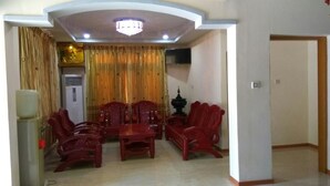 A dining area with a table and chairs, a chandelier, and a television on the wall.