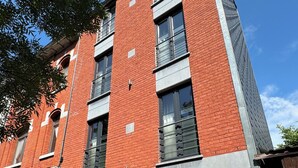 A multi-story building with red brick walls, large windows, and a black garage door.