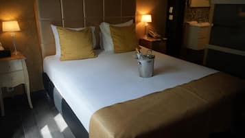 Ein Hotelzimmer mit einem großen Bett, zwei Nachttischen, einer Stehlampe, einem Eimer und einem kleinen Tisch mit einem Telefon.