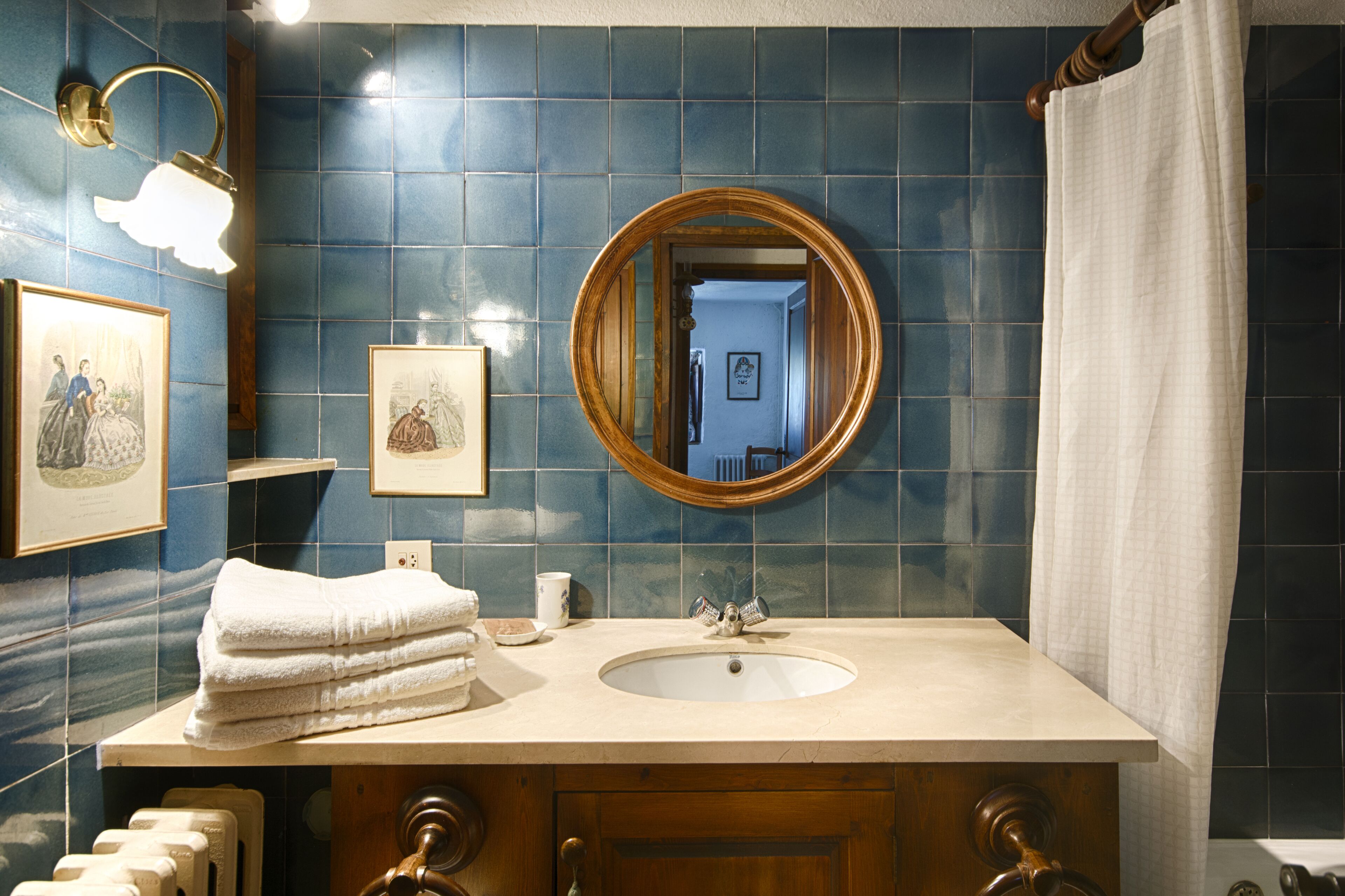 Ein Badezimmer mit Waschbecken, Spiegel und blauen Fliesen.
