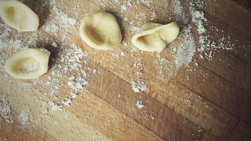 A wooden surface with flour and uncooked pasta shapes.