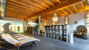 Een wellnessruimte met ligbedden, een stenen muur met planken en een houten plafond.