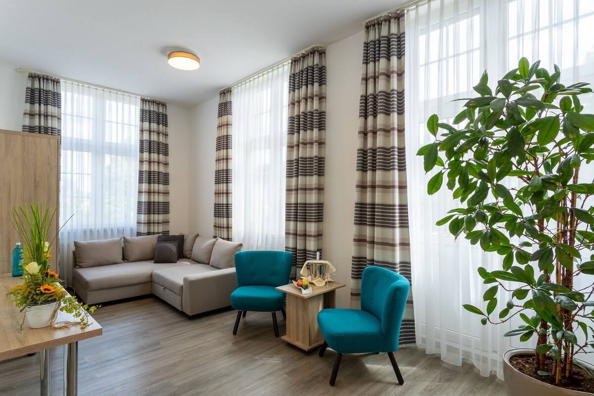 Un salon moderne avec un canapé, deux fauteuils, une table basse et une plante en pot.
