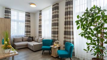 A modern living room with a sofa, two armchairs, a coffee table, and a potted plant.