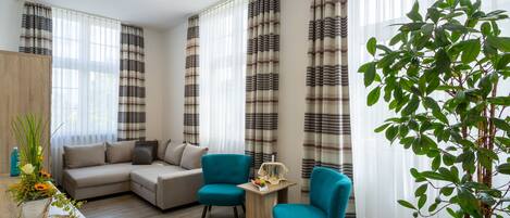 A modern living room with a sofa, two armchairs, a coffee table, and a potted plant.