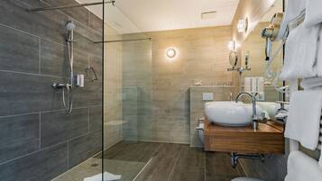 Un baño moderno con cabina de ducha de vidrio, tocador de madera con lavabo y un inodoro.