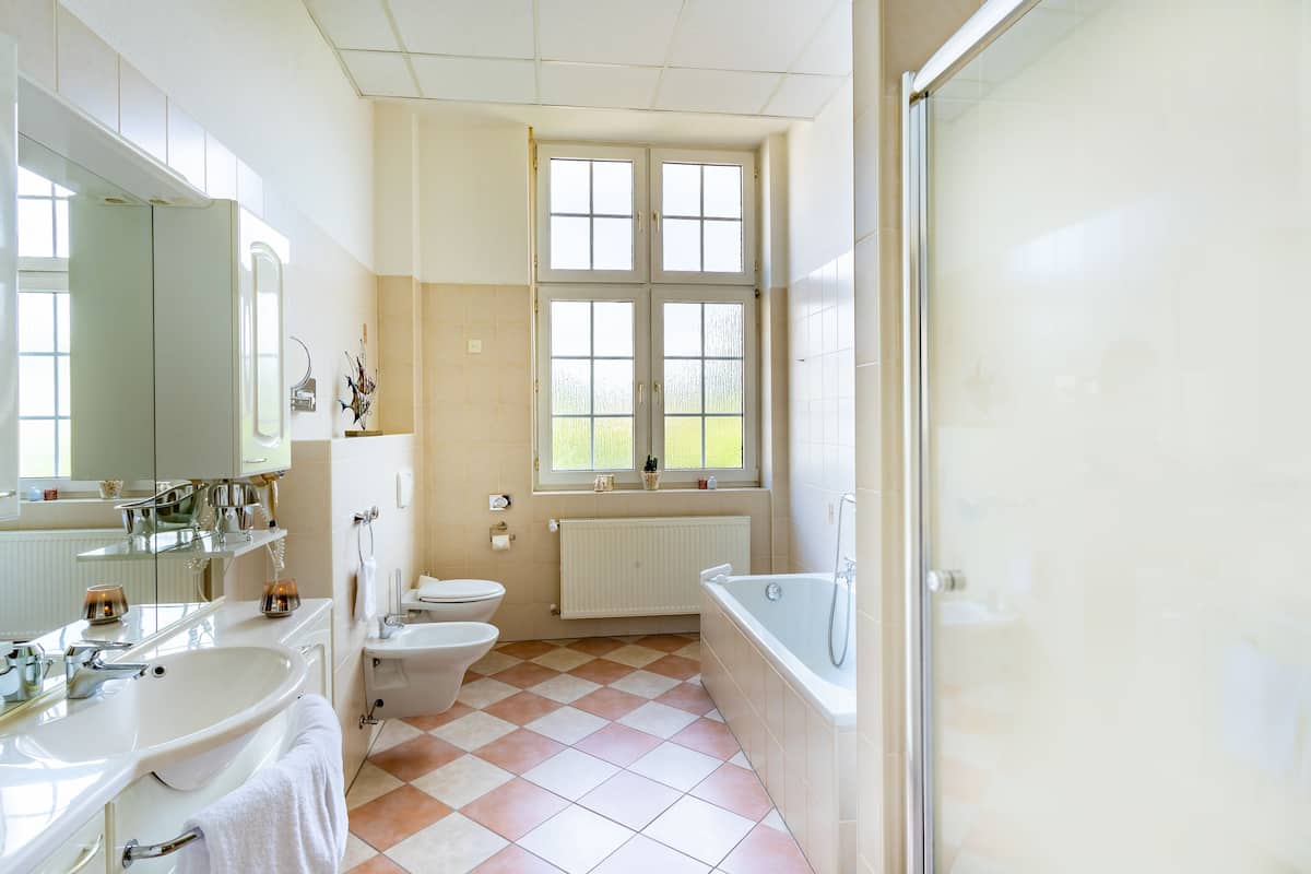 Une salle de bain avec une grande fenêtre, une baignoire, des toilettes et un lavabo.
