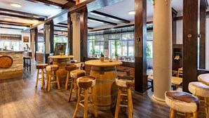 Een restaurant met houten barstoelen, een centraal geplaatst houten vat en grote ramen die natuurlijk licht binnenlaten.