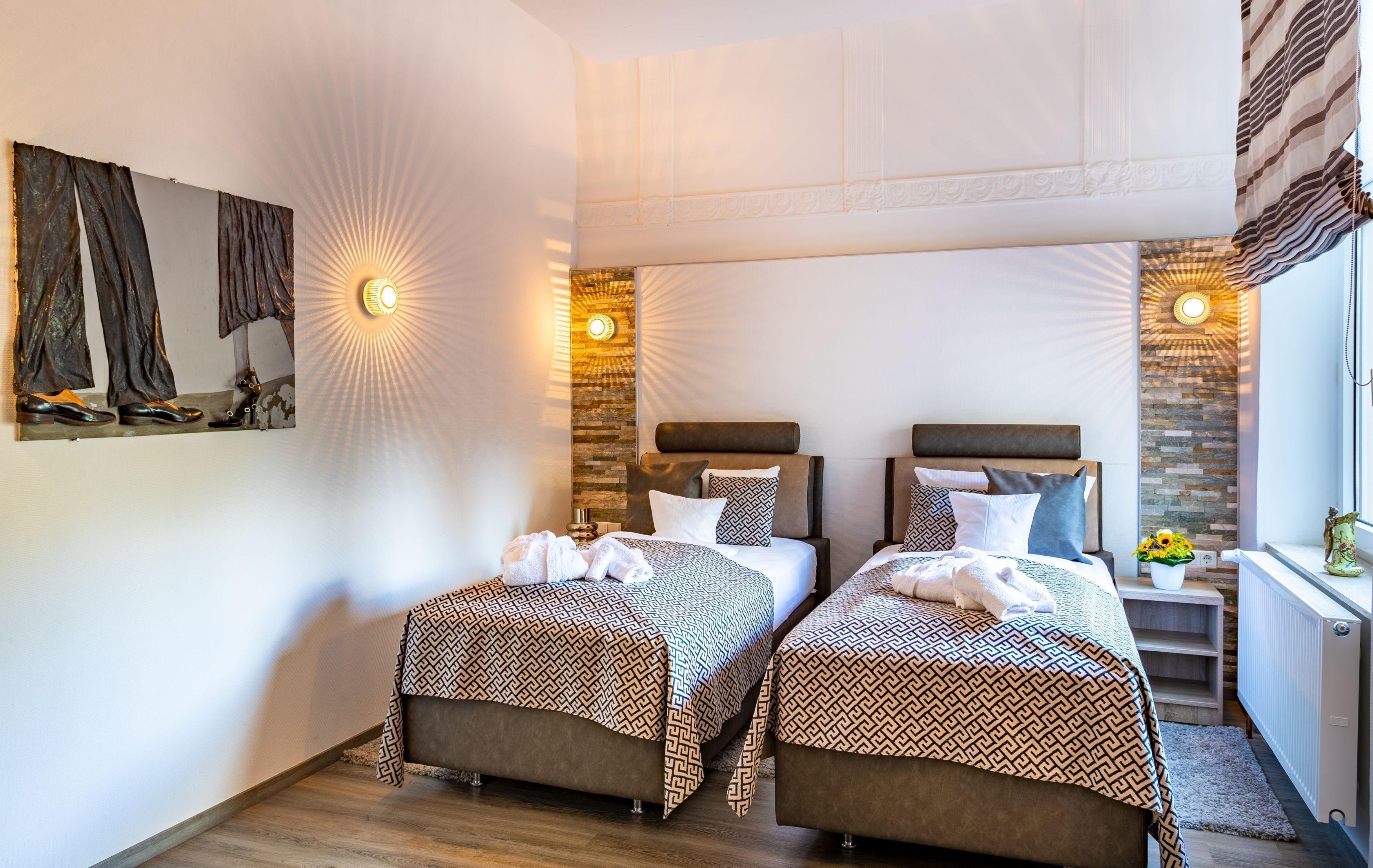 A hotel room with two beds, a large mirror, and decorative wall lights.