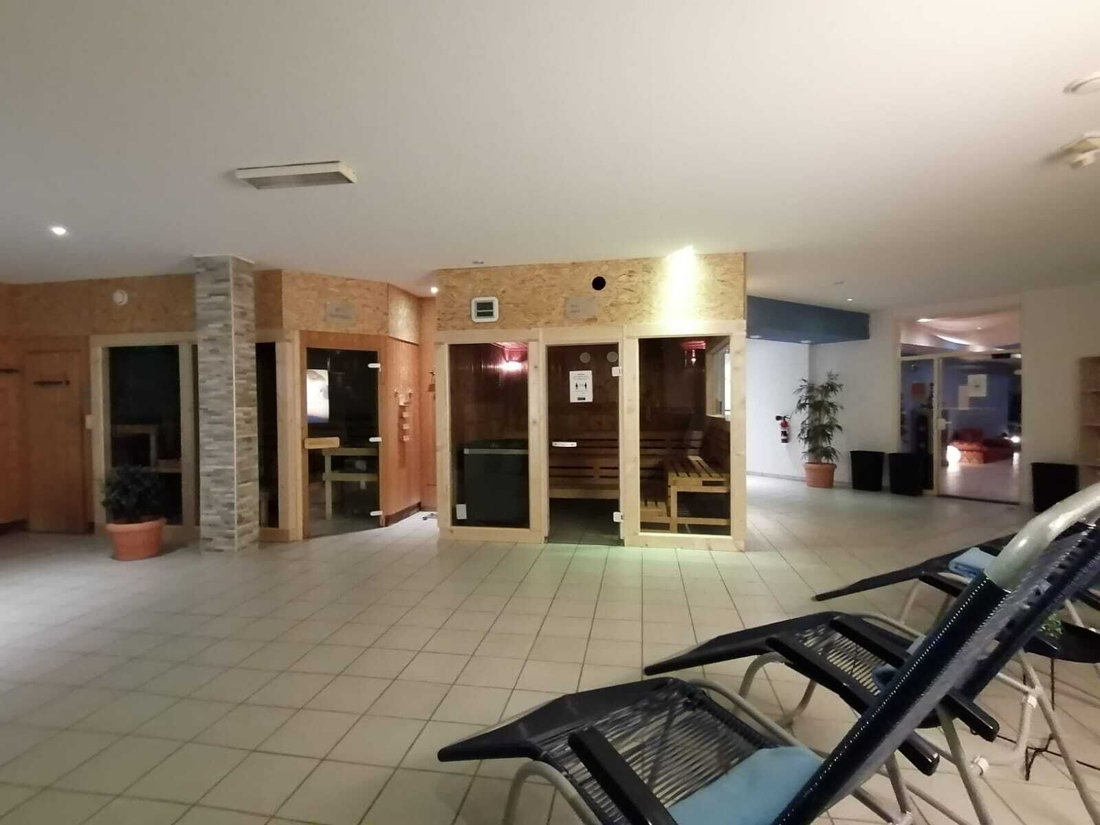 A spacious indoor area with tiled flooring, wooden walls, and a seating area with chairs.