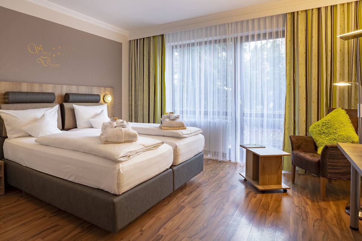 Ein Hotelzimmer mit einem großen Bett, Nachttischen, einem Schreibtisch und Blick ins Freie.