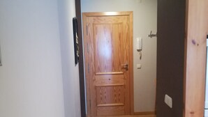 Un pasillo estrecho con piso de madera y una puerta de madera al final.