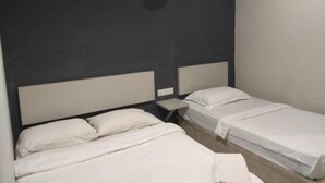 A room with two beds, a small table, and a hanging light fixture. - My Homie Hotel PJ (Petaling Jaya)