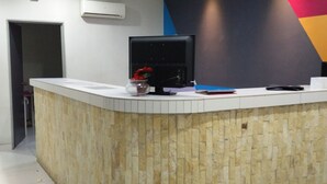 A reception desk with a stone facade, air conditioning unit, and a modern wall with geometric patterns. - My Homie Hotel PJ (Petaling Jaya)