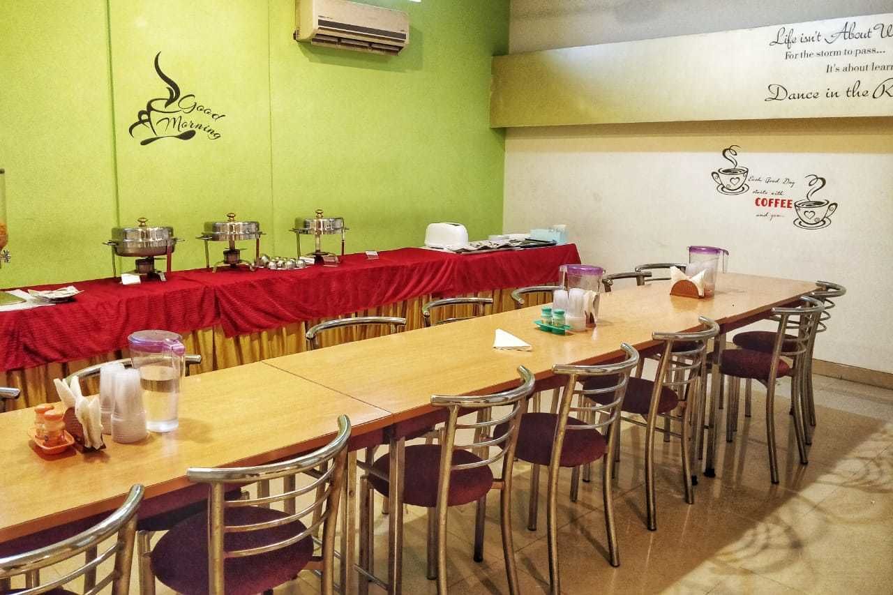 Una sala de conferencias con una larga mesa, sillas y un mantel rojo. Hay decoraciones en la pared y un diseño de taza de café.