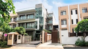 A modern residential building with multiple floors, balconies, and a gated entrance.